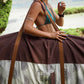 This image features a person carrying a surfboard, which is covered with a mid-length canvas surfboard cover. The cover displays a unique sandy brown tone, reminiscent of the South Australian coastlines.